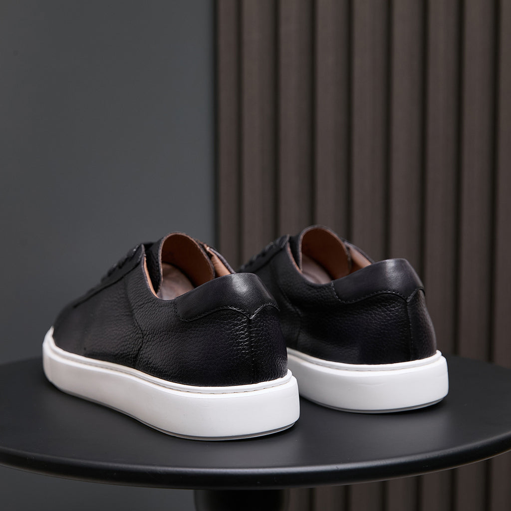 Black leather sneakers with rear heel tabs and white rubber outsole