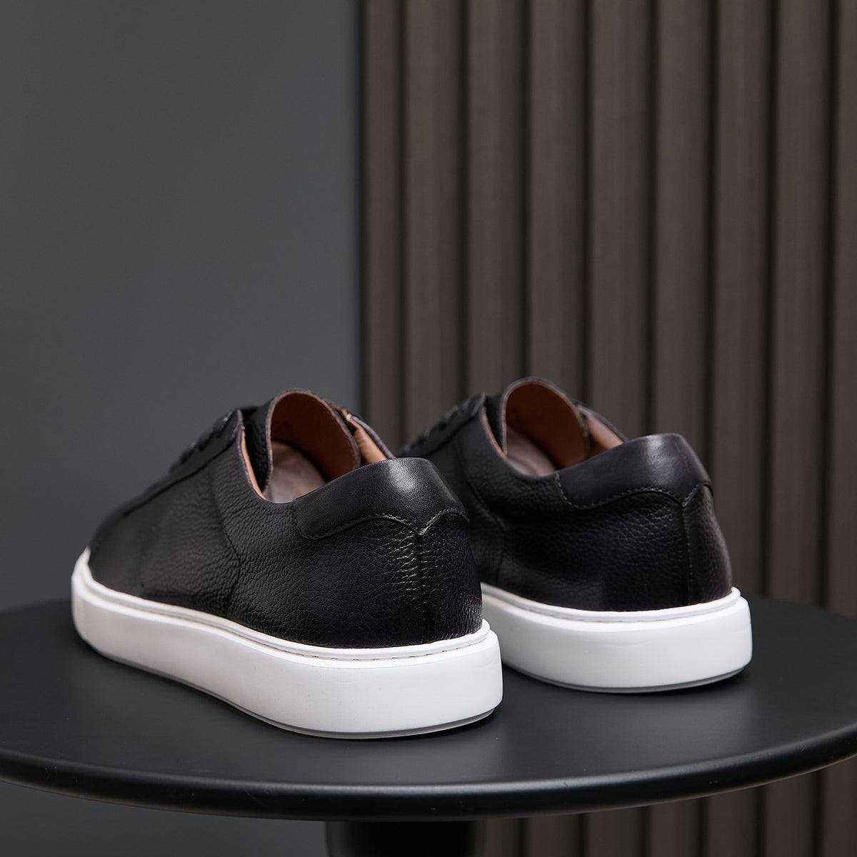 Black leather sneakers with rear heel tabs and white rubber outsole