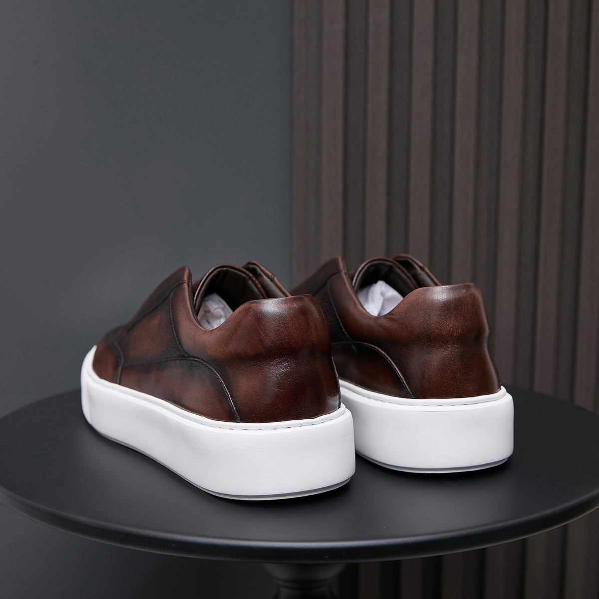 Brown leather sneakers viewed from the back with white platform sole