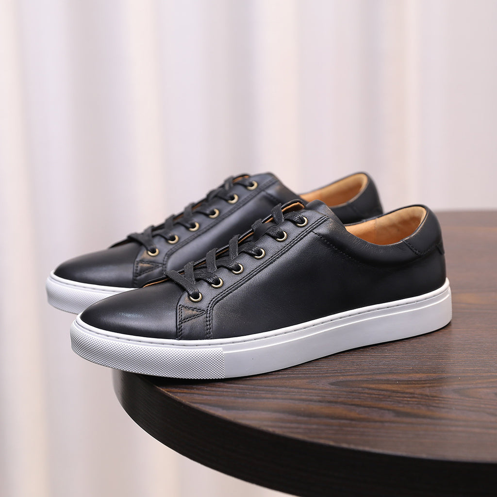 Black leather low-top sneakers with white rubber outsole and lace-up front.