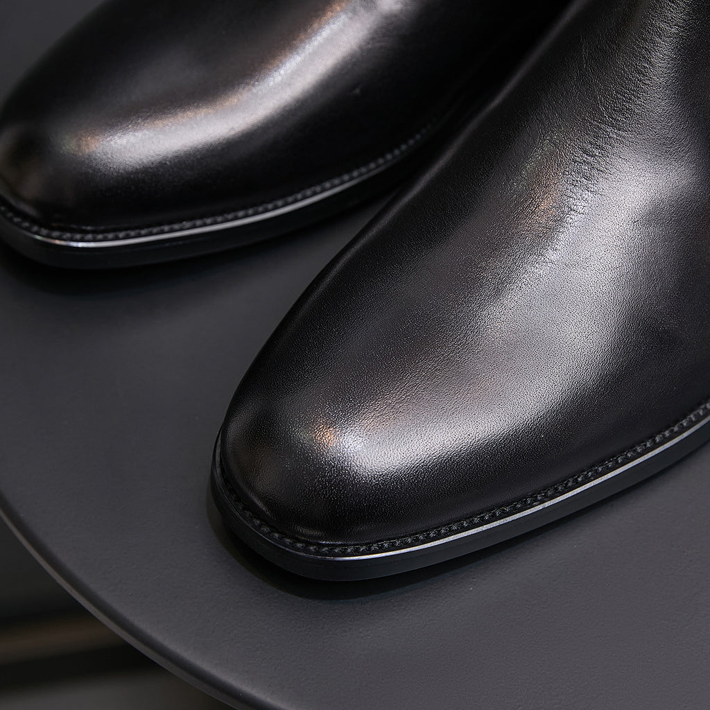 Black leather pointed cap toe dress boot with side zip detail, close-up