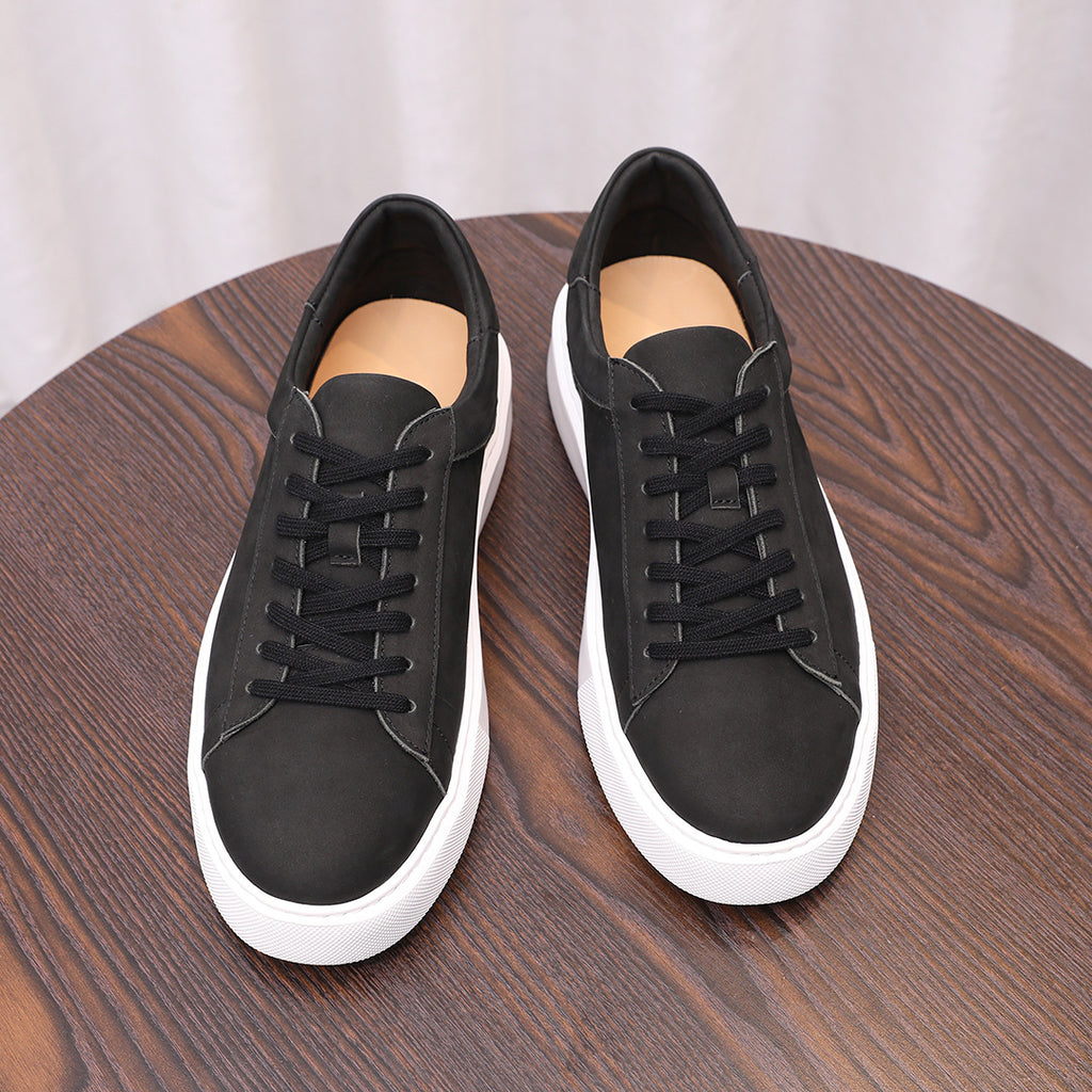 Pair of black leather sneakers with black laces and white rubber outsole
