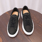 Pair of black leather sneakers with black laces and white rubber outsole