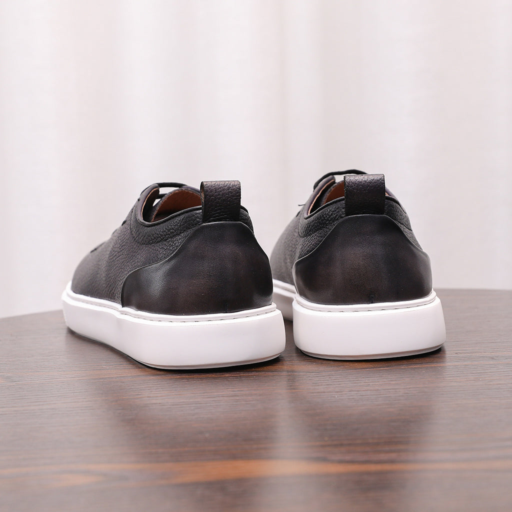 Pair of black genuine leather sneakers, back view with heel tab and white rubber soles.