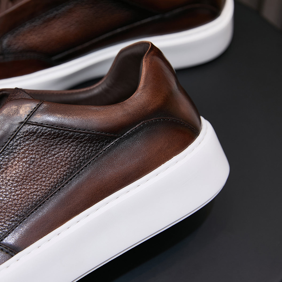 Brown leather sneaker side panel close-up with textured uppers and white sole