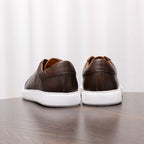 Men's dark brown leather sneakers, rear view with white midsoles and heel panels