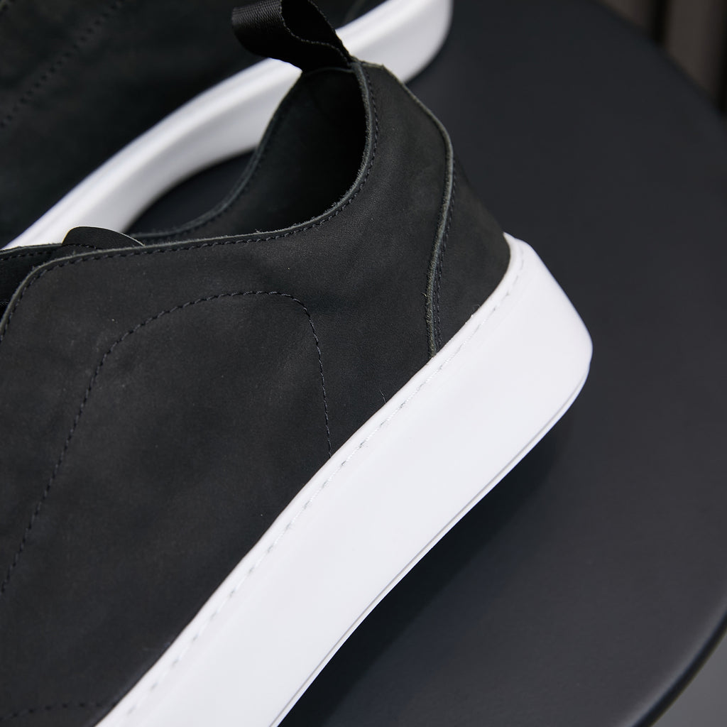 Black leather slip-on sneaker with side panel stitching and white rubber sole.