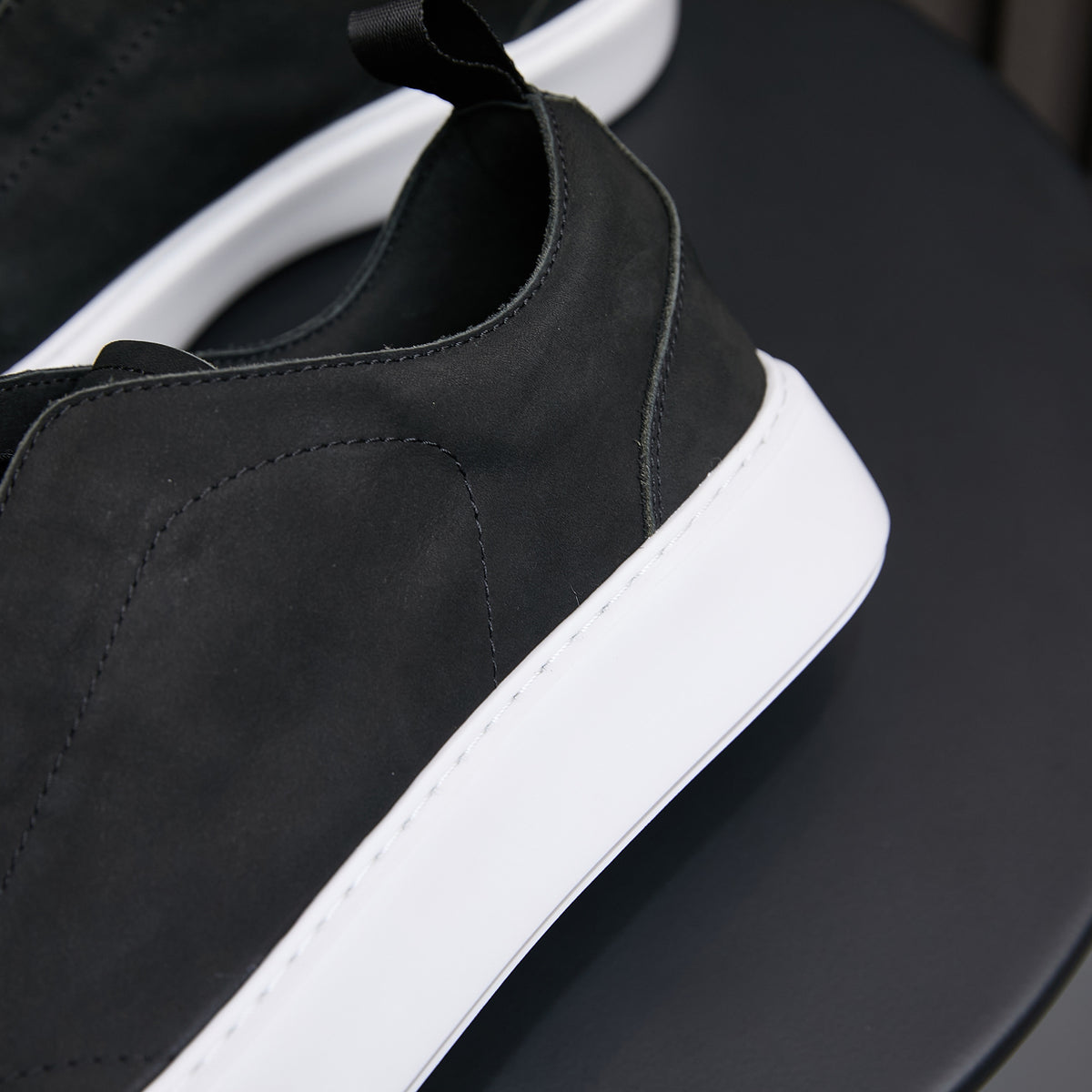 Black leather slip-on sneaker with side panel stitching and white rubber sole.