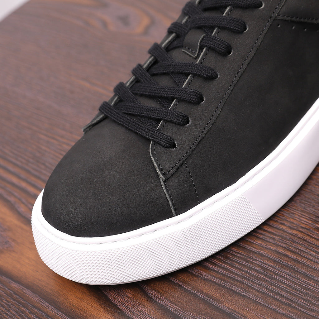 Close-up of black leather sneaker toe and lace-up eyelets with white sole edge