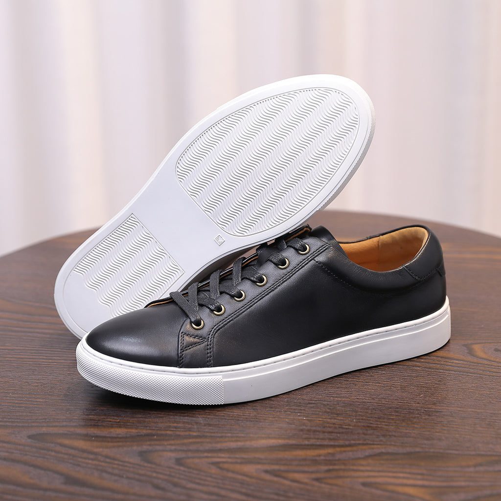 Black leather sneakers with white rubber outsole and textured tread bottom.