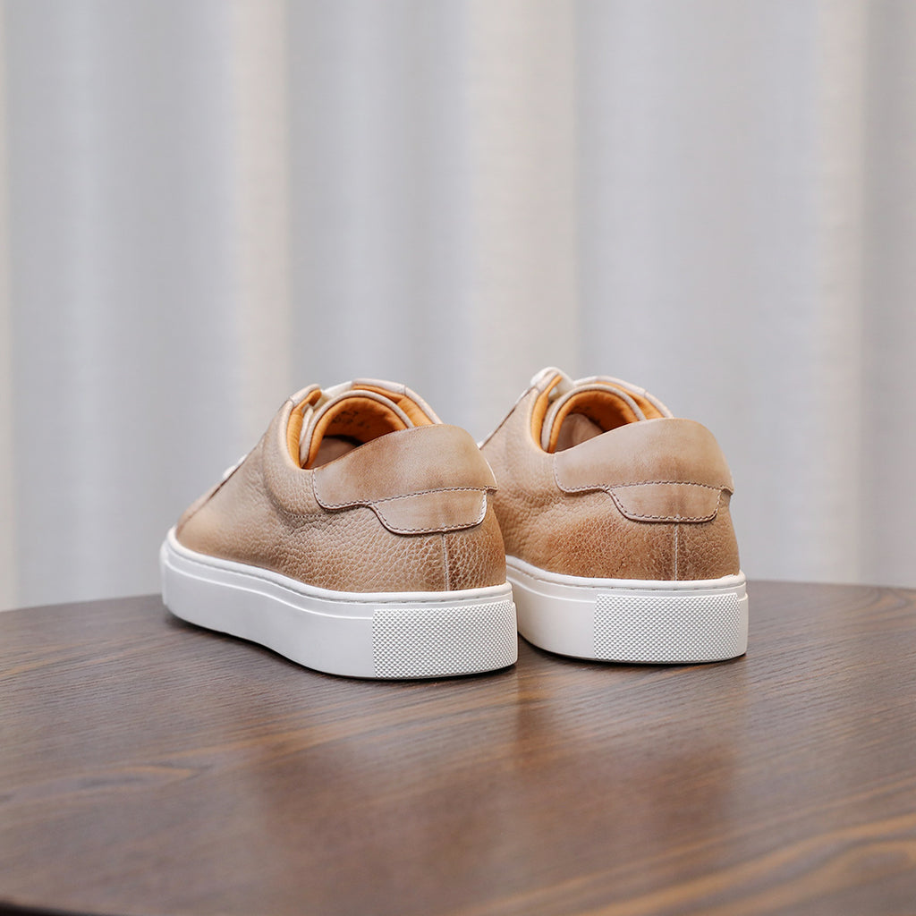 Beige leather sneakers, rear view, with white rubber sole and padded collar