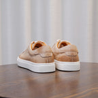Beige leather sneakers, rear view, with white rubber sole and padded collar