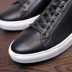 Men's black leather sneakers close-up, lace-up eyelets and white rubber sole