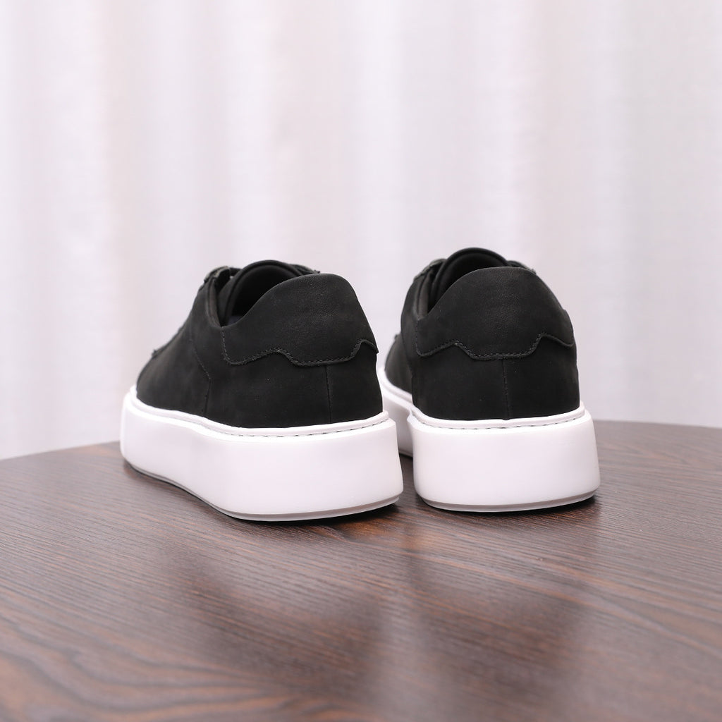 Black leather sneakers with rear heel tabs and white rubber soles