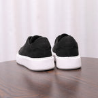Black leather sneakers with rear heel tabs and white rubber soles