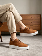 Brown leather lace-up sneakers with thick white sole and cushioned collar