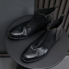 Black leather pointed-toe dress boots with side zipper and low heel