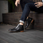 Men's black leather pointed-toe dress boots with side zipper and brown sole trim