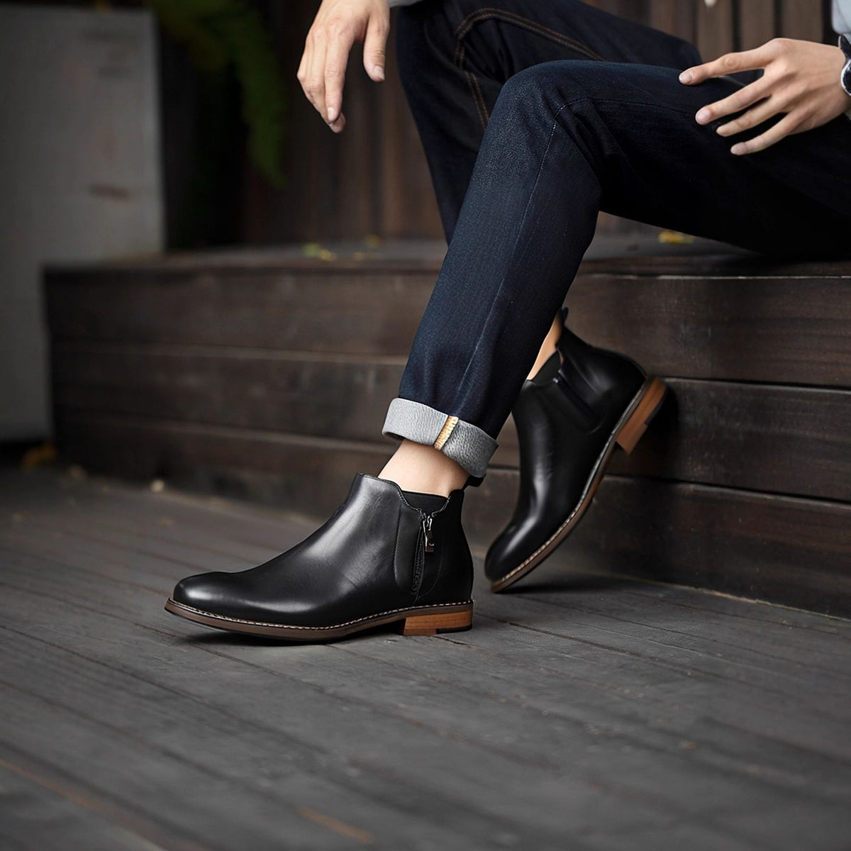 Men's black leather pointed-toe dress boots with side zipper and brown sole trim