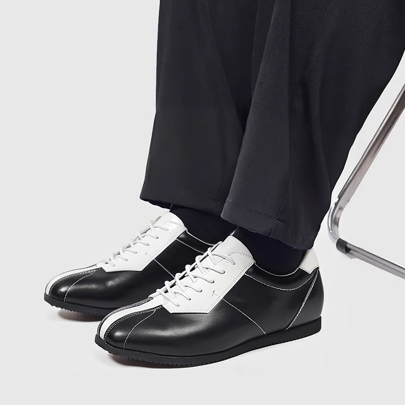 Black leather sneakers with white trim, lace-up closure, and rounded toe cap.