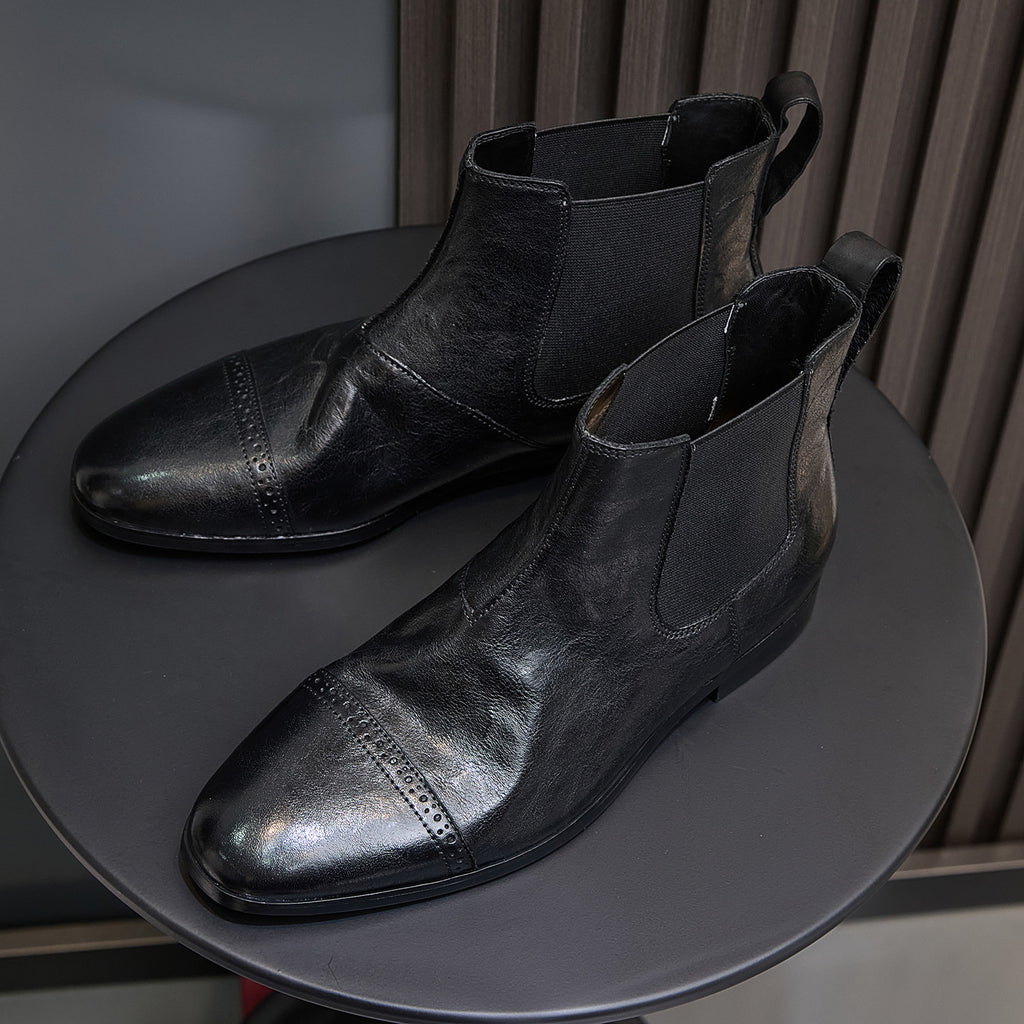 Black pointed-toe Chelsea dress boots with elastic sides and subtle perforation