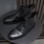 Black pointed-toe Chelsea dress boots with elastic sides and subtle perforation