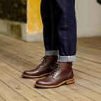 Brown leather pointed-cap toe lace-up side-zip boots worn with dark jeans cuffs