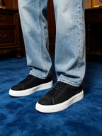 Black leather low-top sneakers with black laces and white rubber sole