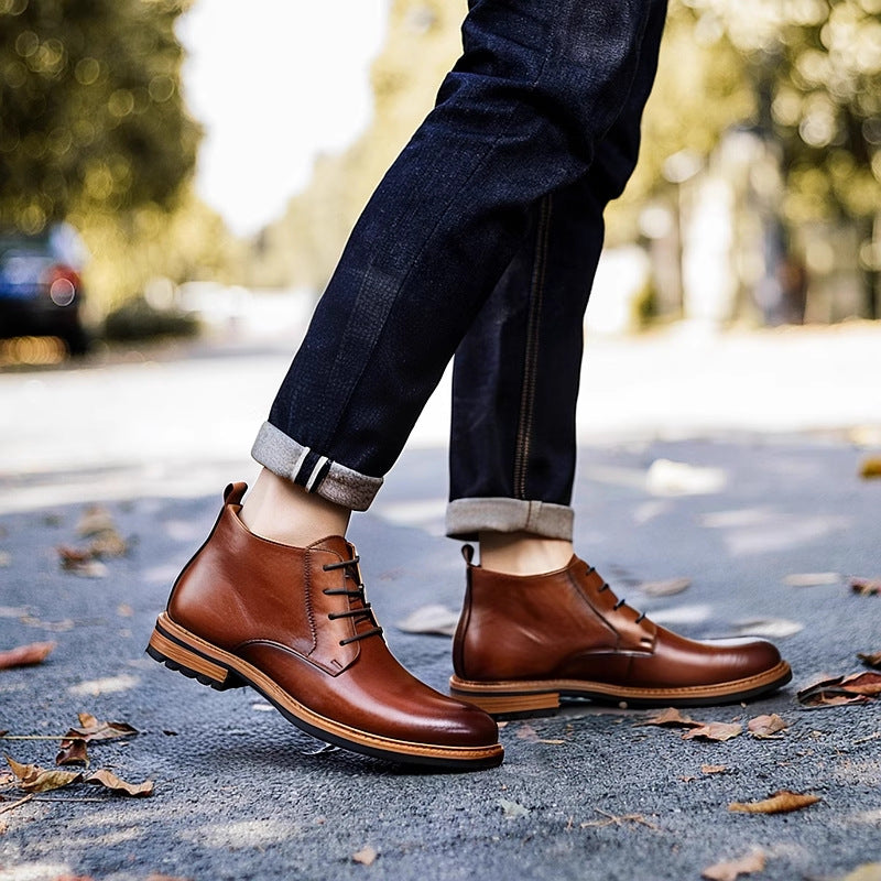 Brown leather lace-up chukka boots on pavement, plain toe with rugged tread outsole.