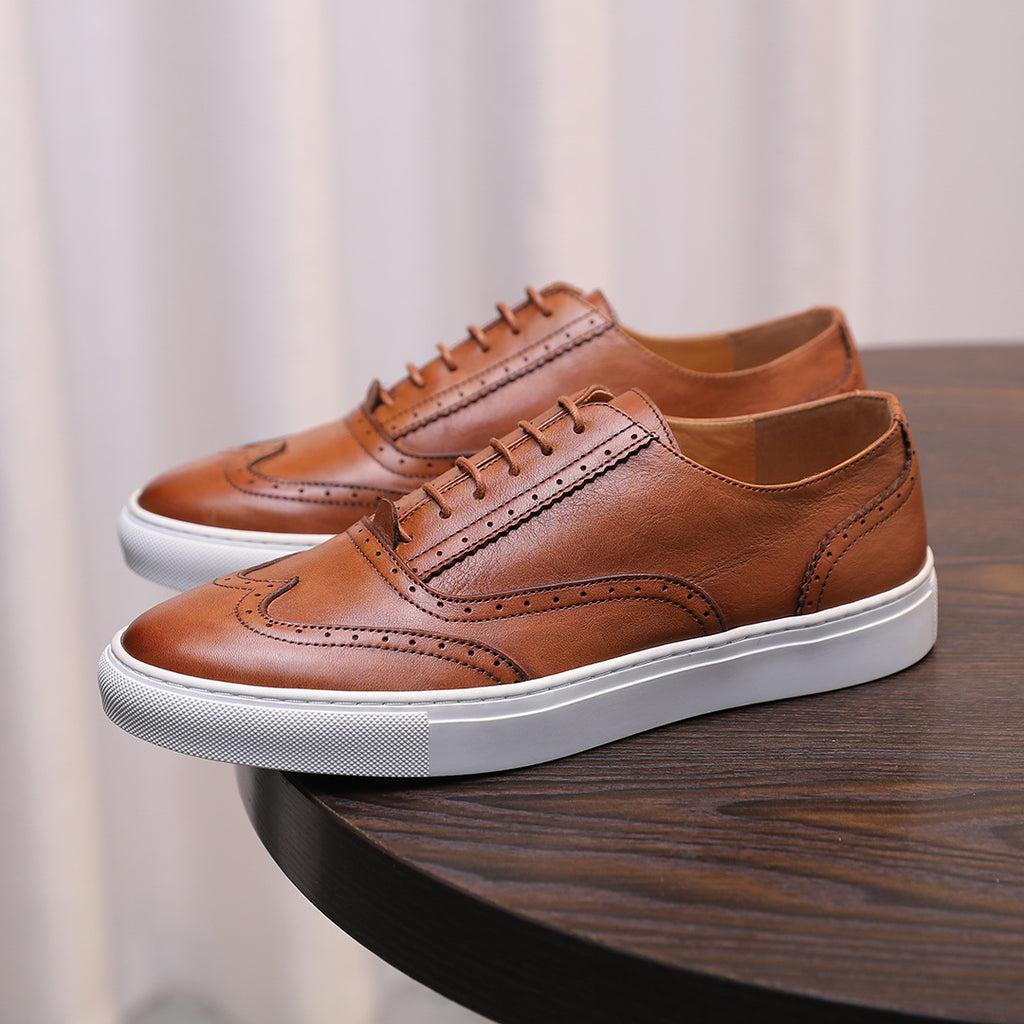 Men's brown leather lace-up sneakers with wingtip-style stitching and white sole