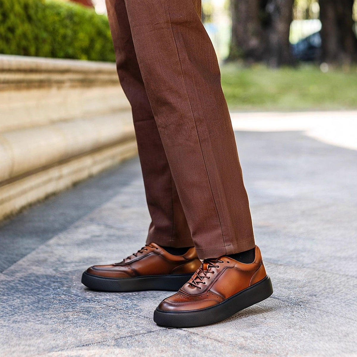 Men's leather sneakers, brown, lace-up with perforated panels and thick rubber sole.