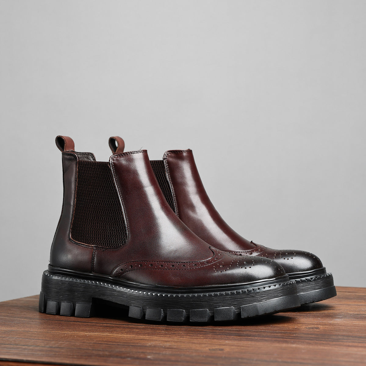 Brown leather chelsea dress boots with elastic gore, wingtip perforations, thick lug sole
