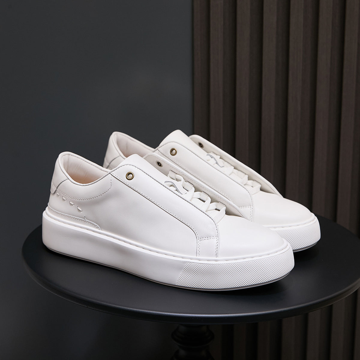 Men's white leather sneakers with lace-up eyelets and textured white sole
