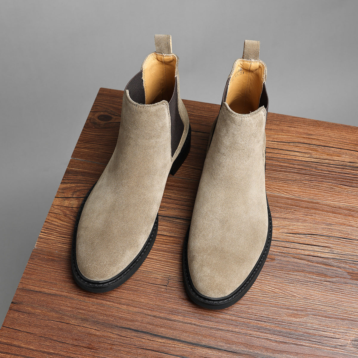 Pair of taupe Chelsea dress boots with side elastic gore and low stacked heel.