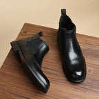 Men's black leather chelsea dress boots, slip-on elastic gore, wingtip-style toe.