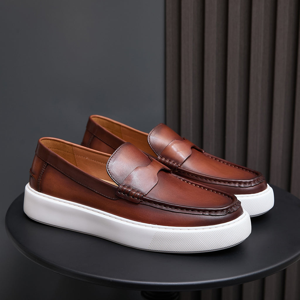 Pair of brown leather slip-on sneakers with moccasin stitching and white platform sole