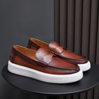 Pair of brown leather slip-on sneakers with moccasin stitching and white platform sole