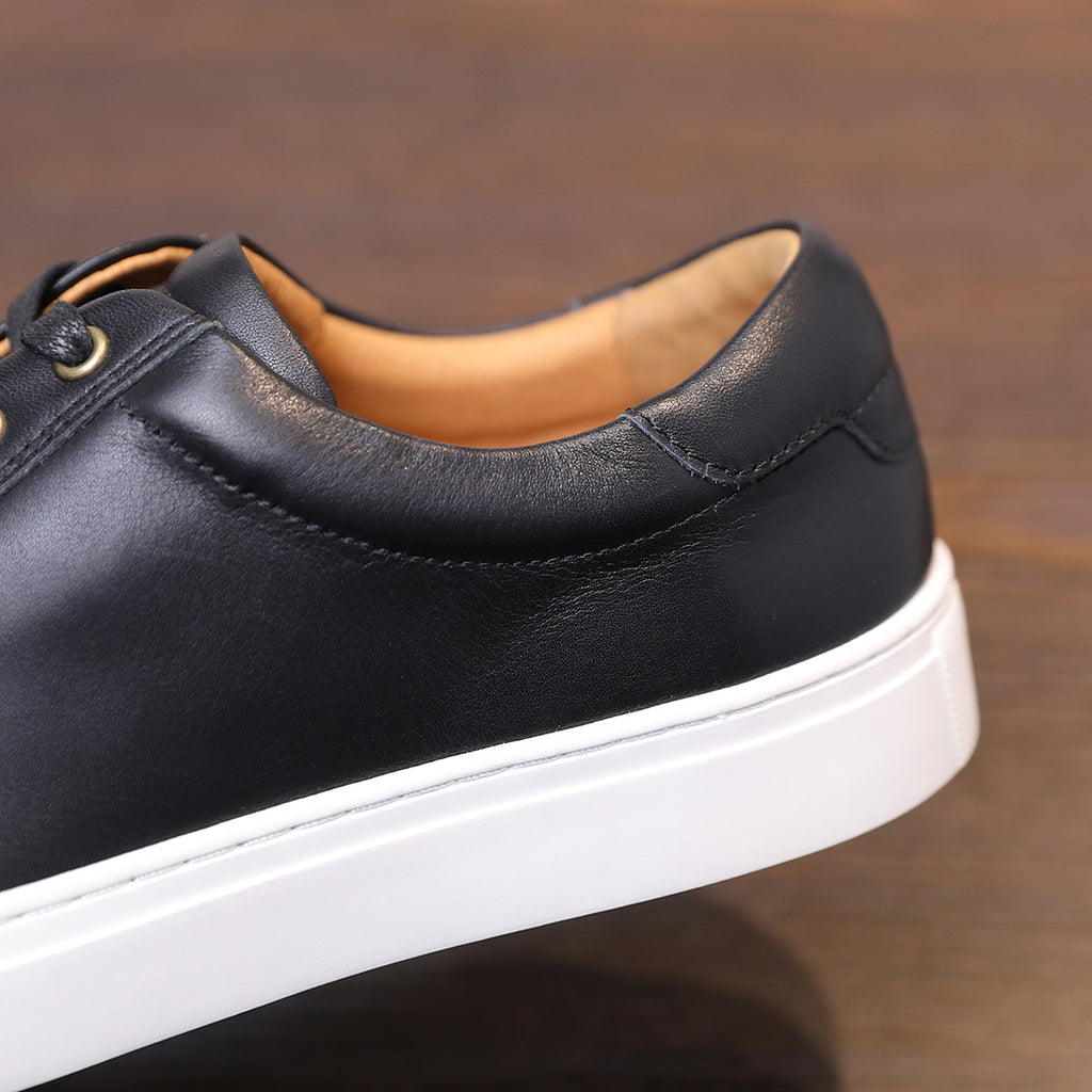 Men's black leather sneakers side view, padded collar and white platform sole