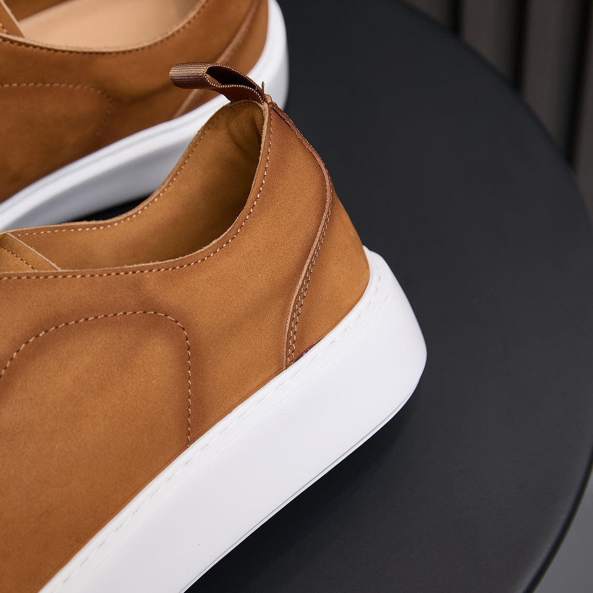 Men's genuine leather sneakers close-up: brown leather upper with white sole and stitched trim
