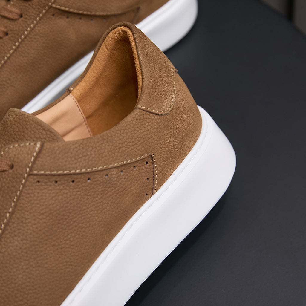 Brown leather sneaker close-up: padded collar with white rubber sole