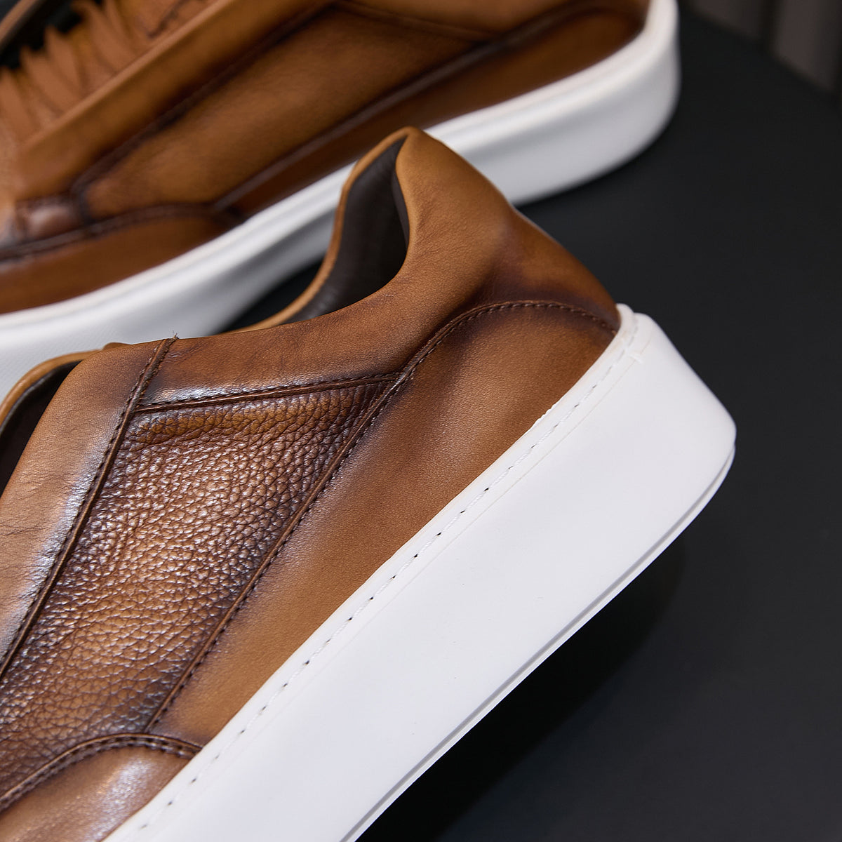 Brown leather sneaker side close-up with white midsole and clean stitching