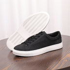 Men's genuine leather sneaker showing outsole tread; dark upper, black laces, white sole