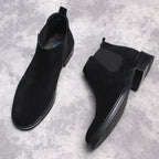 Men's black Chelsea dress boots, angled pair showing low heel and stitched trim