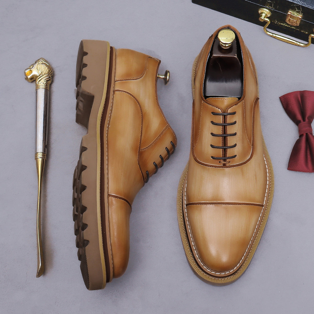 Tan lace-up oxford shoes with brogue/wingtip stitching and chunky lug sole, angled view.