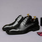 Men's black leather lace-up derby dress shoes, pointed toe with low stacked heel.