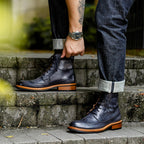 Men's dark leather lace-up chukka boots with tread sole, worn with dark jeans