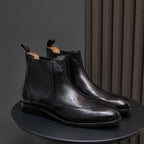 Pointed-toe black chelsea dress boots pair with elastic side panels and low stacked heels