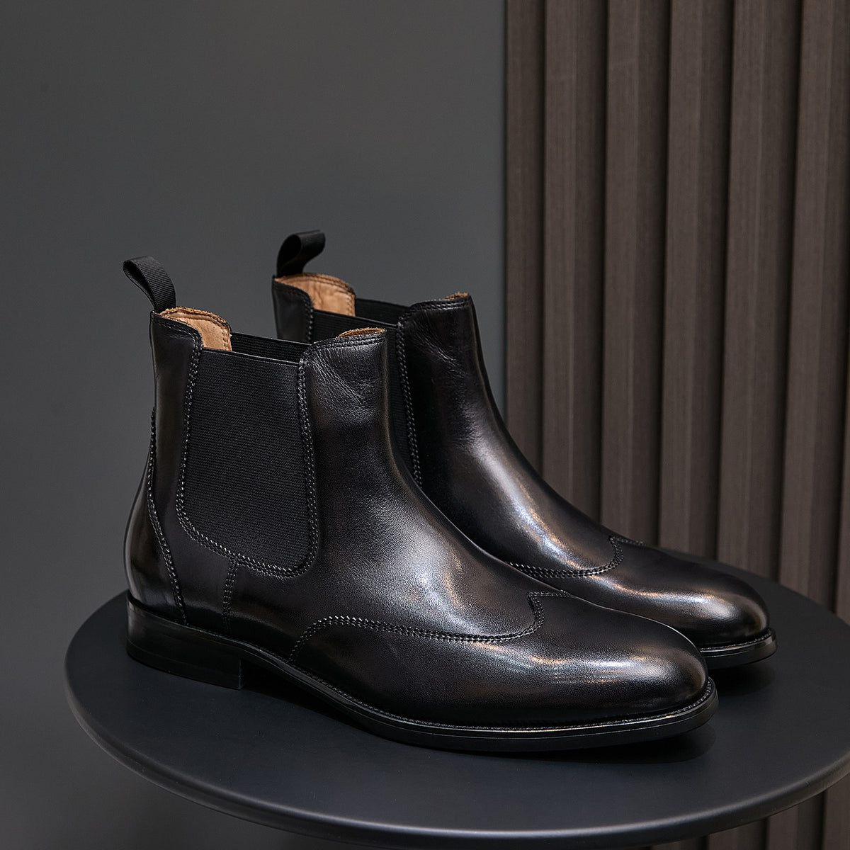 Pointed-toe black chelsea dress boots pair with elastic side panels and low stacked heels