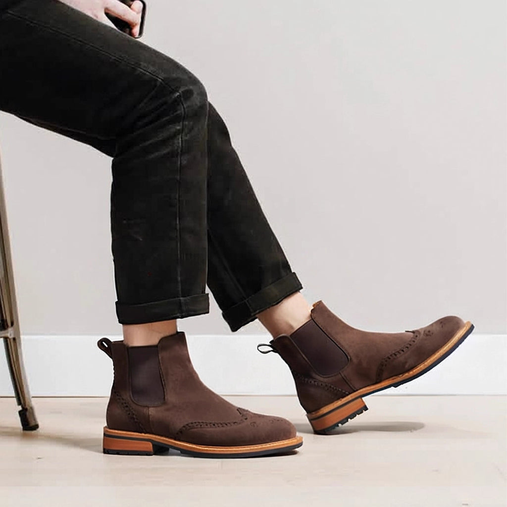 Brown suede pointed-toe Chelsea boots on model with elastic side panels and rubber sole