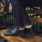 Men's black leather lace-up sneakers, side view with low platform sole